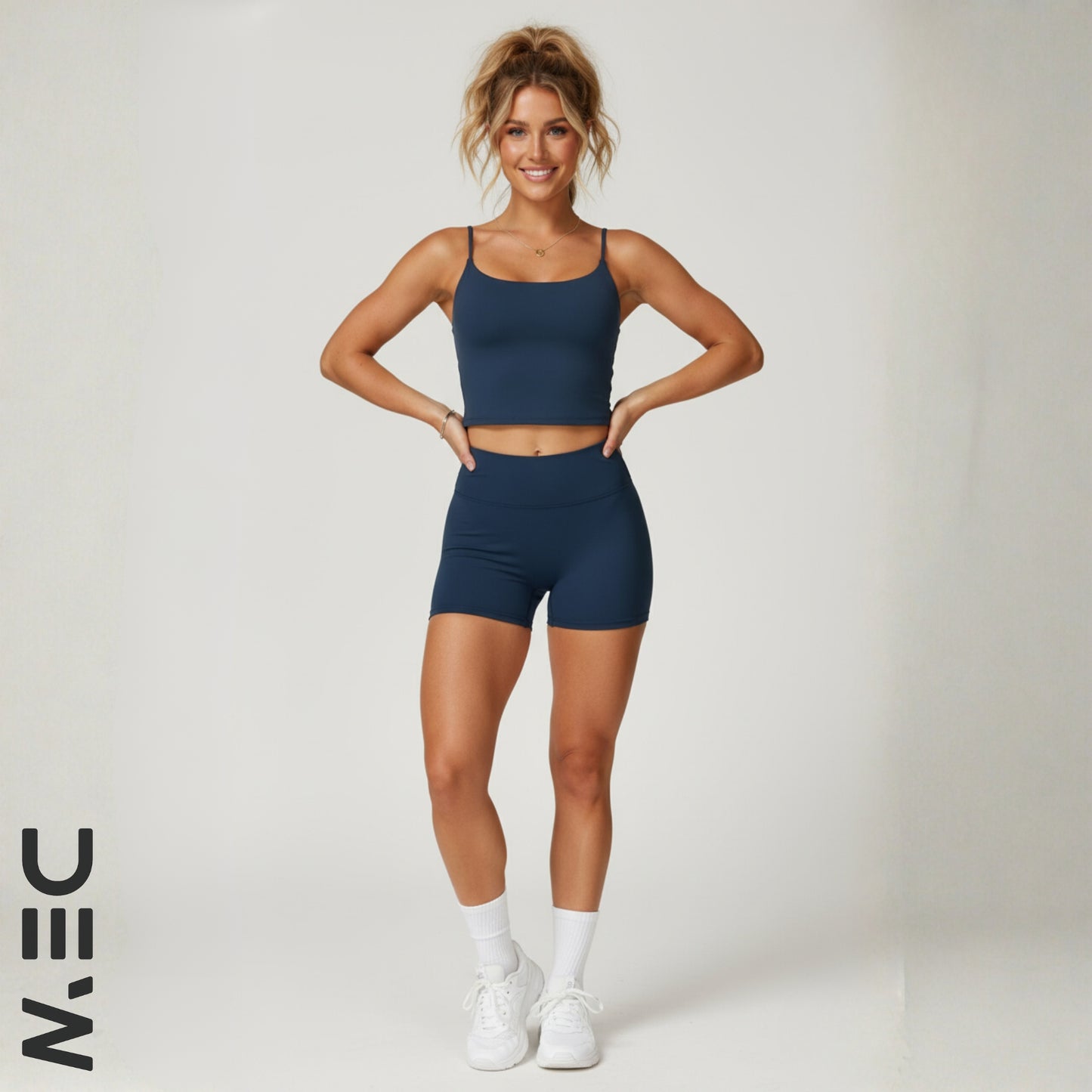 Woman wearing a navy blue dew luxe cami with 'DEW' logo on a white background