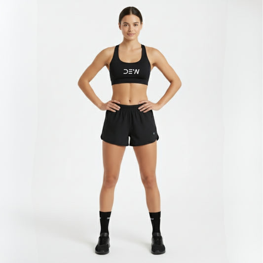 Woman wearing a black sports bra and shorts with 'DEW' branding on a white background