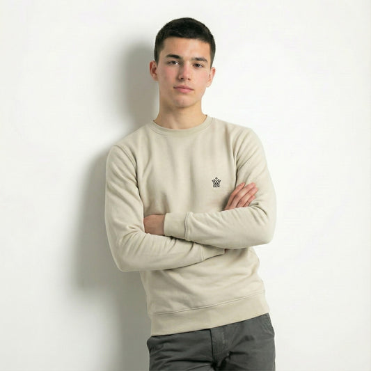 Person wearing a dew caramal jumper with a dew small logo, standing against a plain background