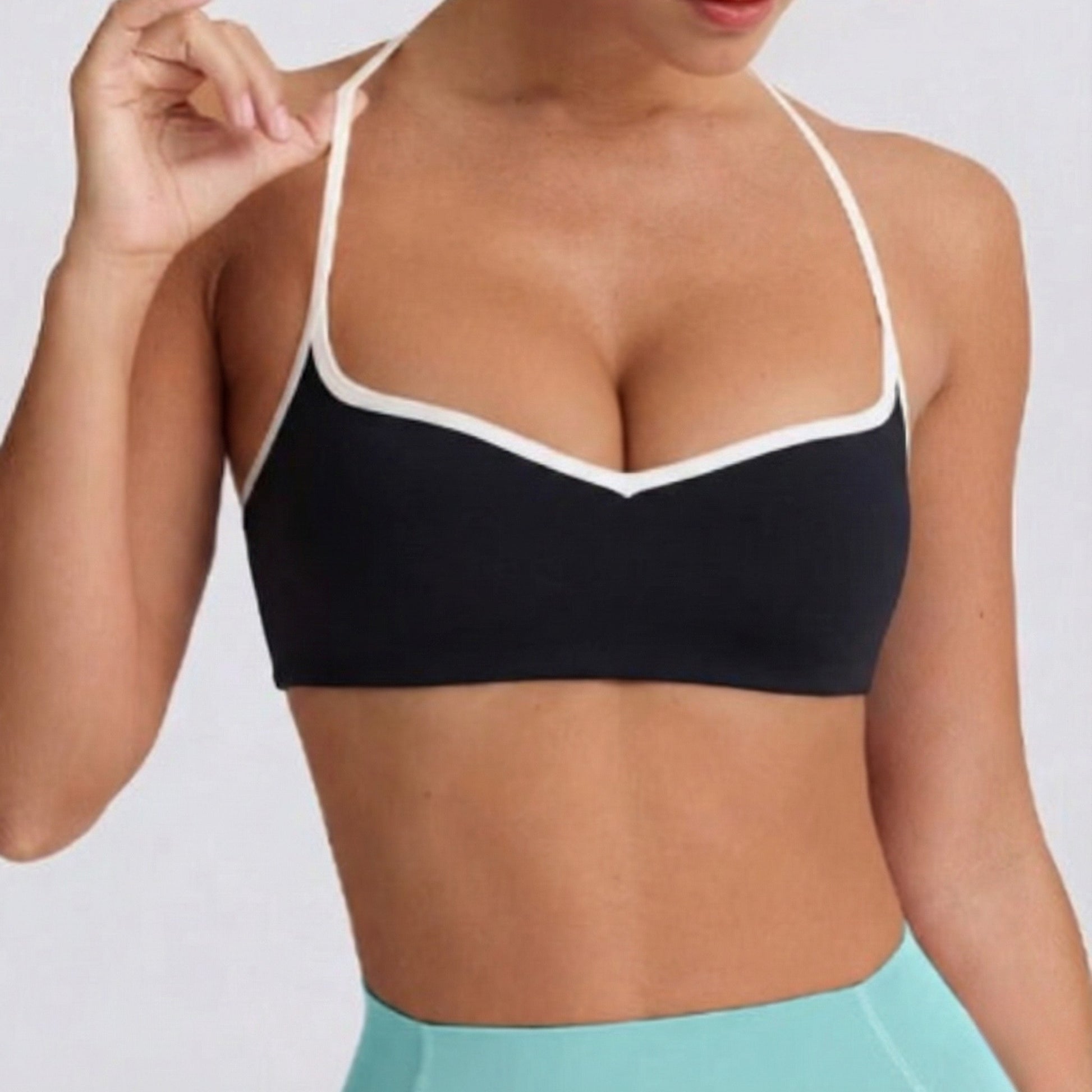 Black DEW Elevate Bra with white trim worn by a person on a plain background
