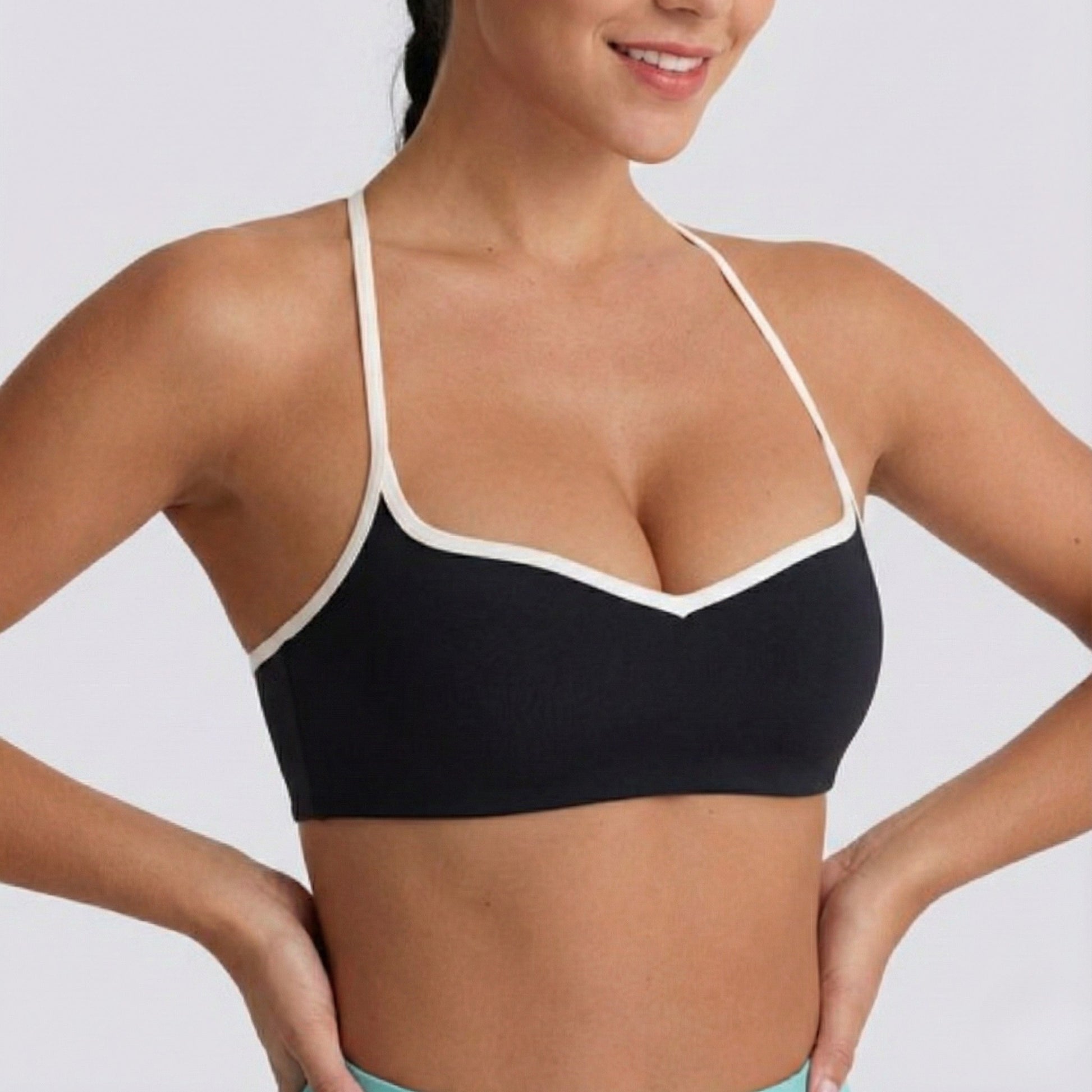 Woman wearing a black DEW Elevate Bra with white trim on a plain background