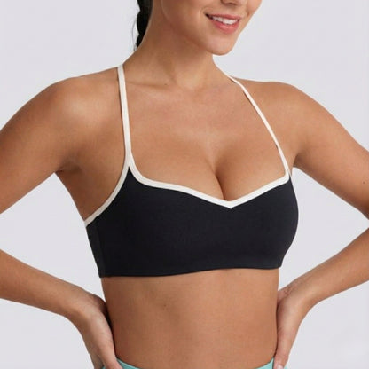 Woman wearing a black DEW Elevate Bra with white trim on a plain background