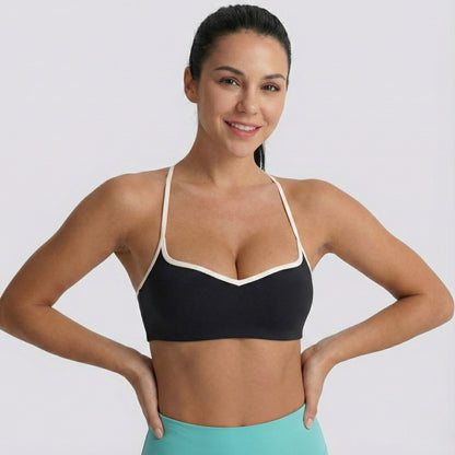 Woman wearing a black DEW Elevate Bra with white straps on a plain background