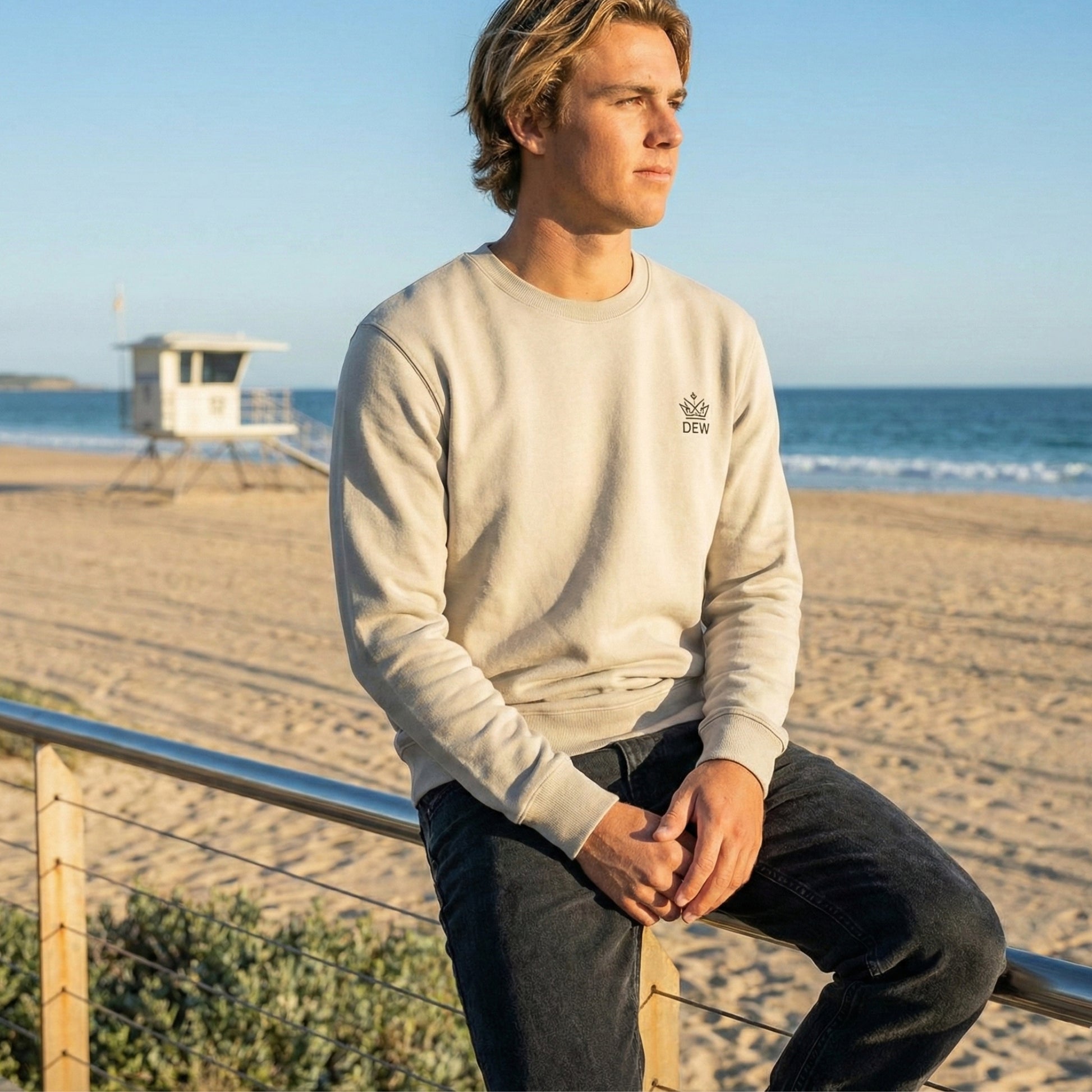 Man sitting on a beach with a scenic view of the ocean and sky.