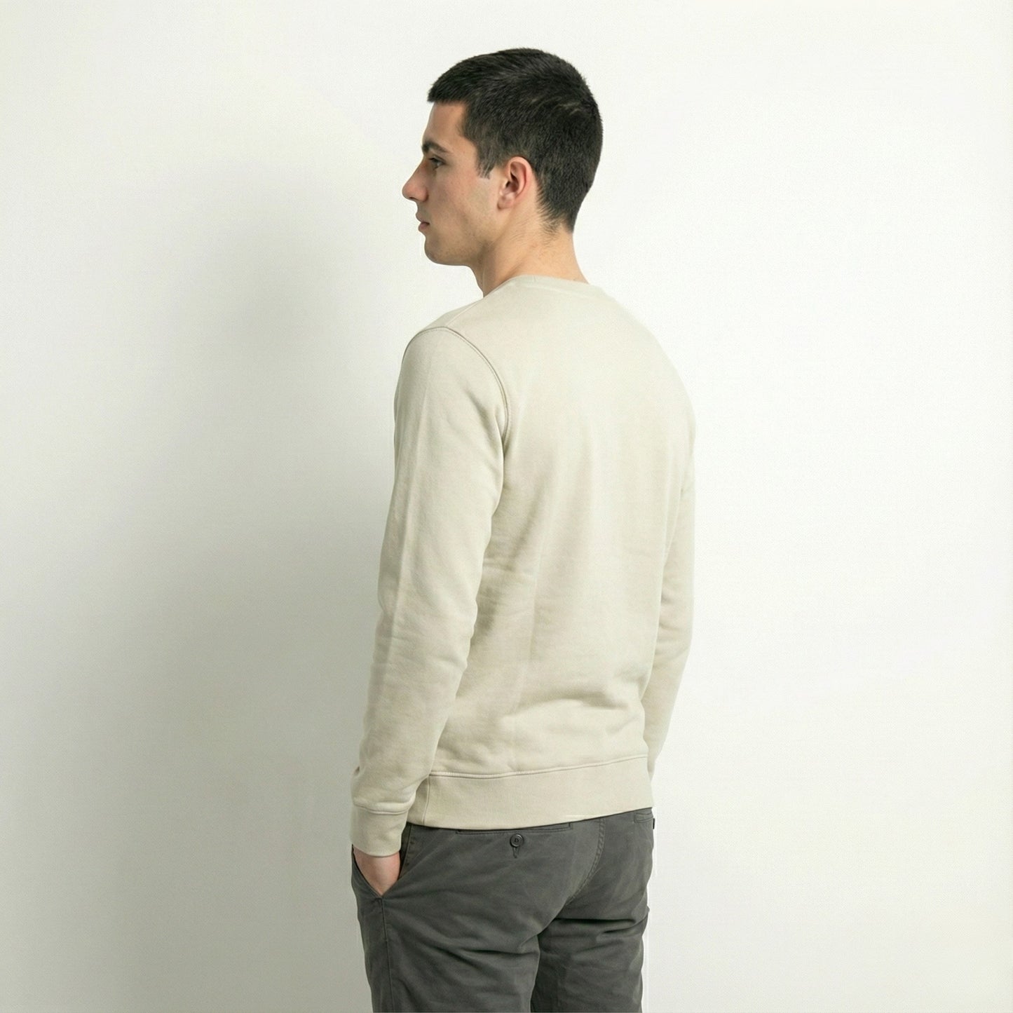 Man wearing a dew caramal jumper and gray pants against a plain background