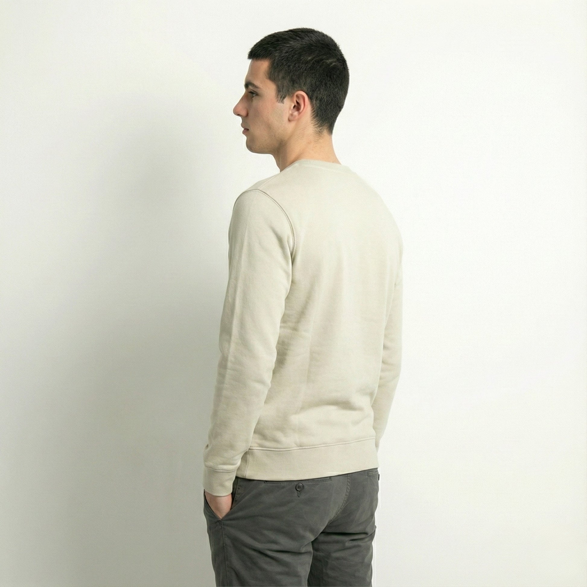 Man wearing a dew caramal jumper and gray pants against a plain background