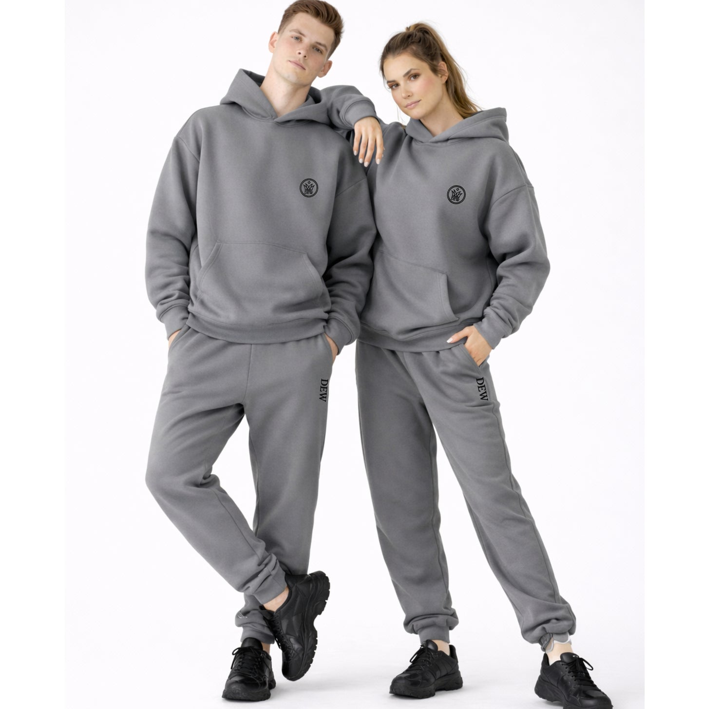 Two people wearing matching gray hoodie and pants sets on a white background