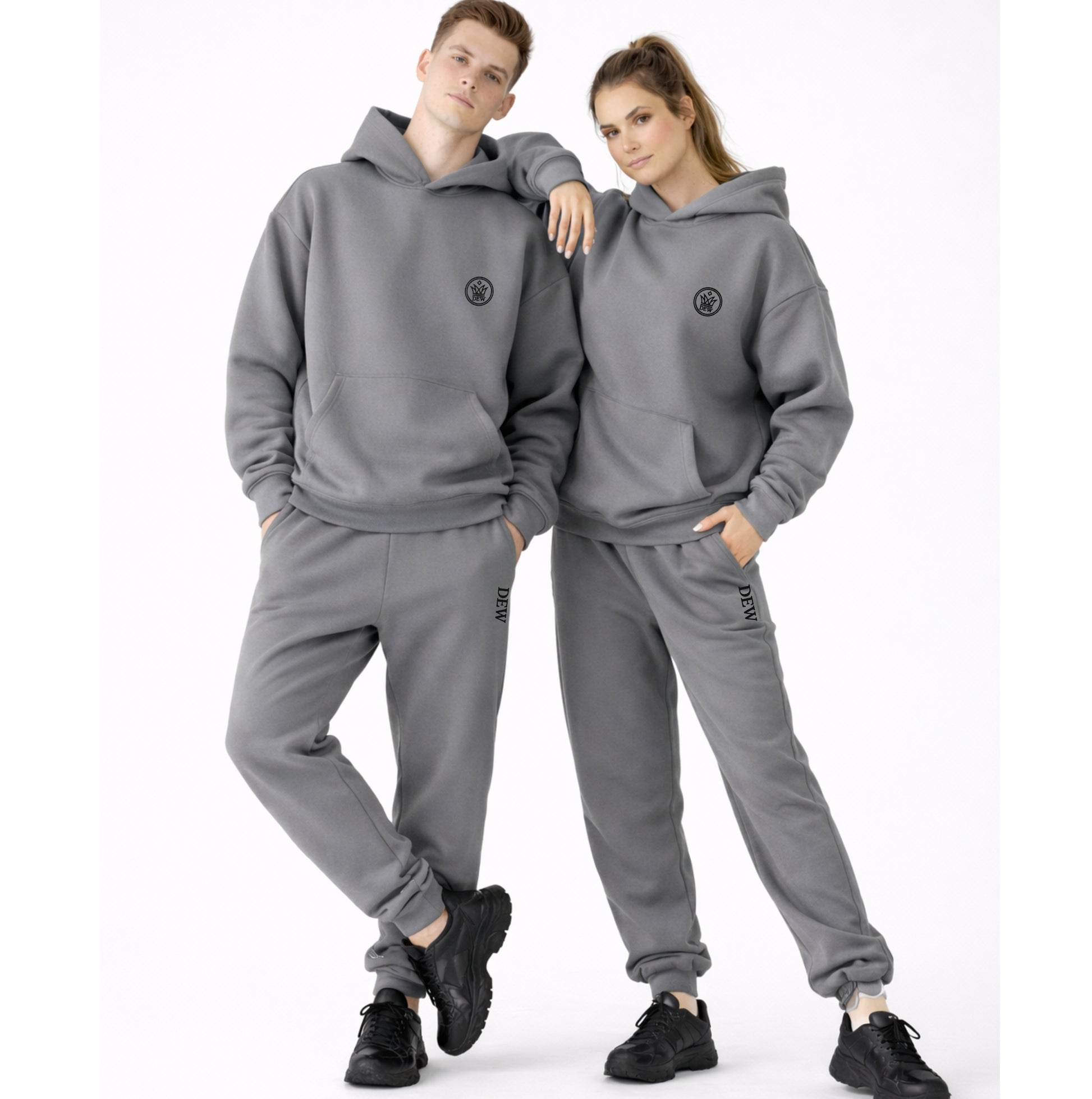 Two people wearing matching gray hoodie and pants sets on a white background
