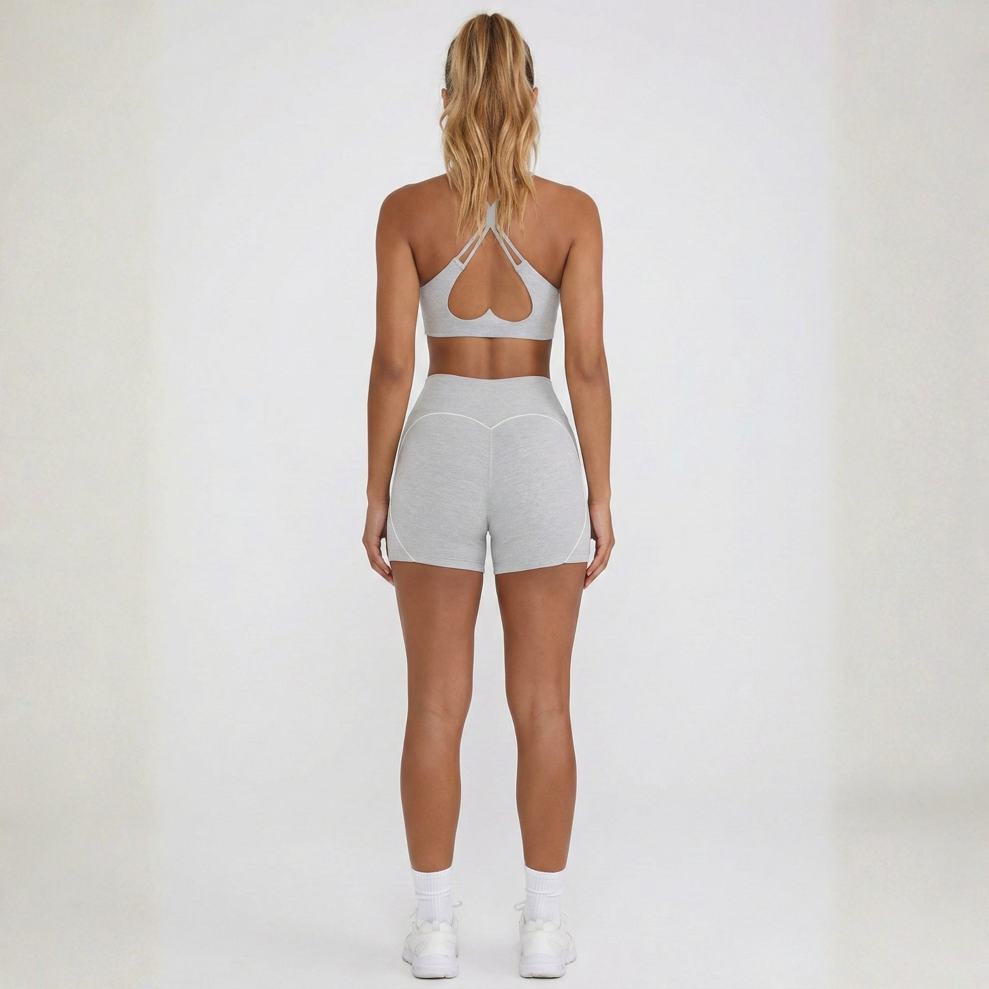 Person wearing a dew gray sports bra and dew curve shorts set on a white background