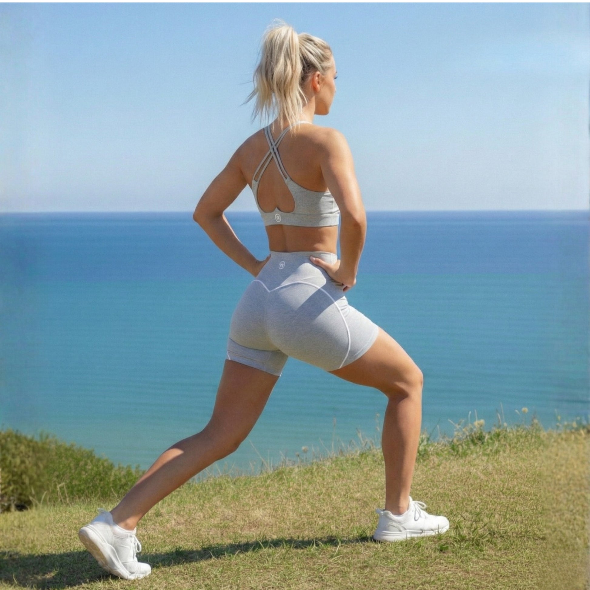 Woman in Dew curve high waisted  shorts standing on a grassy hill overlooking the ocean.
