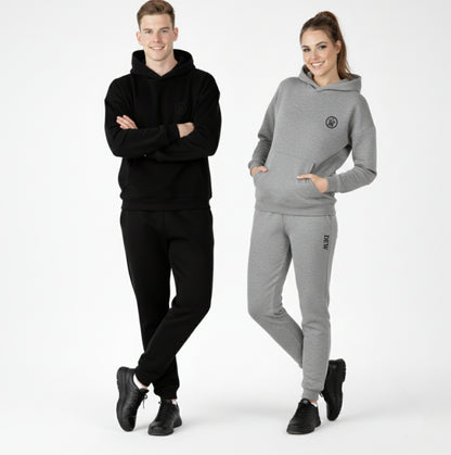 Two people wearing black and gray tracksuits on a white background