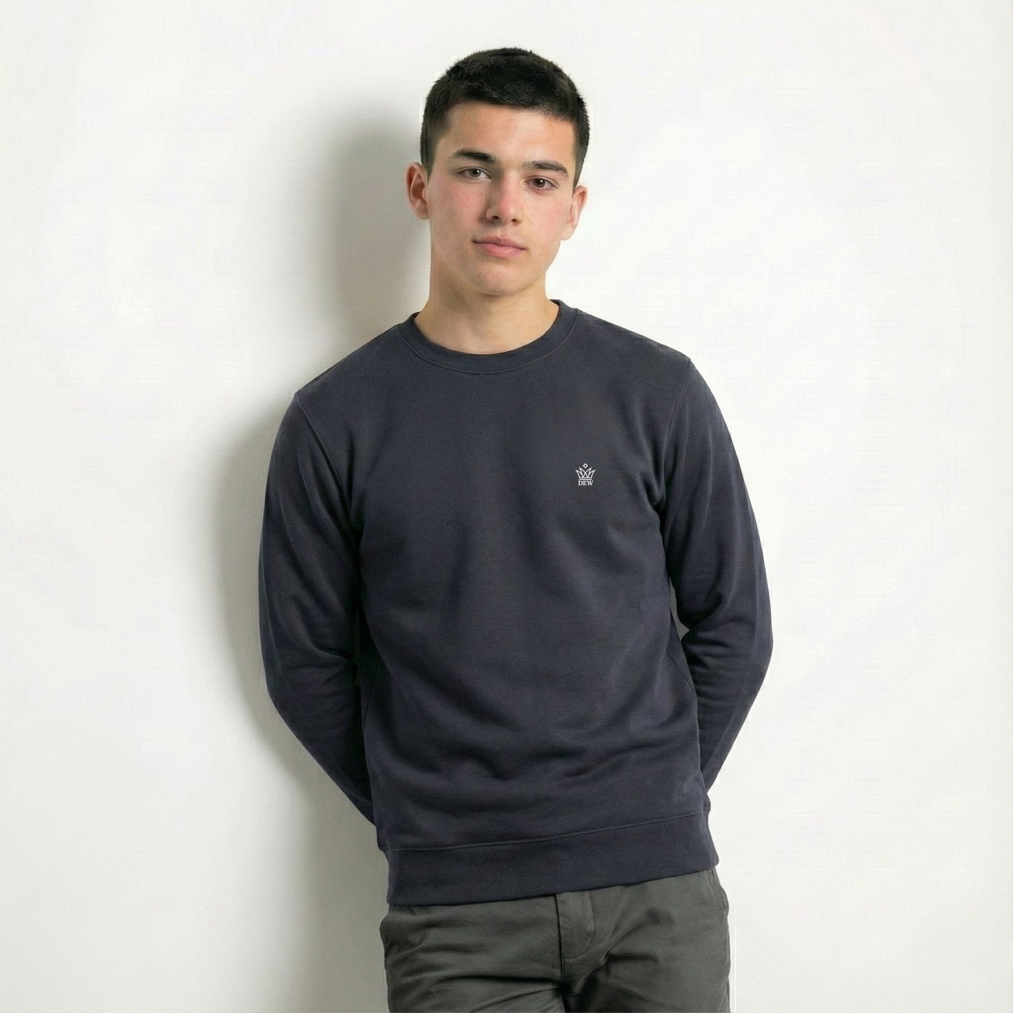 Person wearing a dark gray sweatshirt with a small logo on a white background