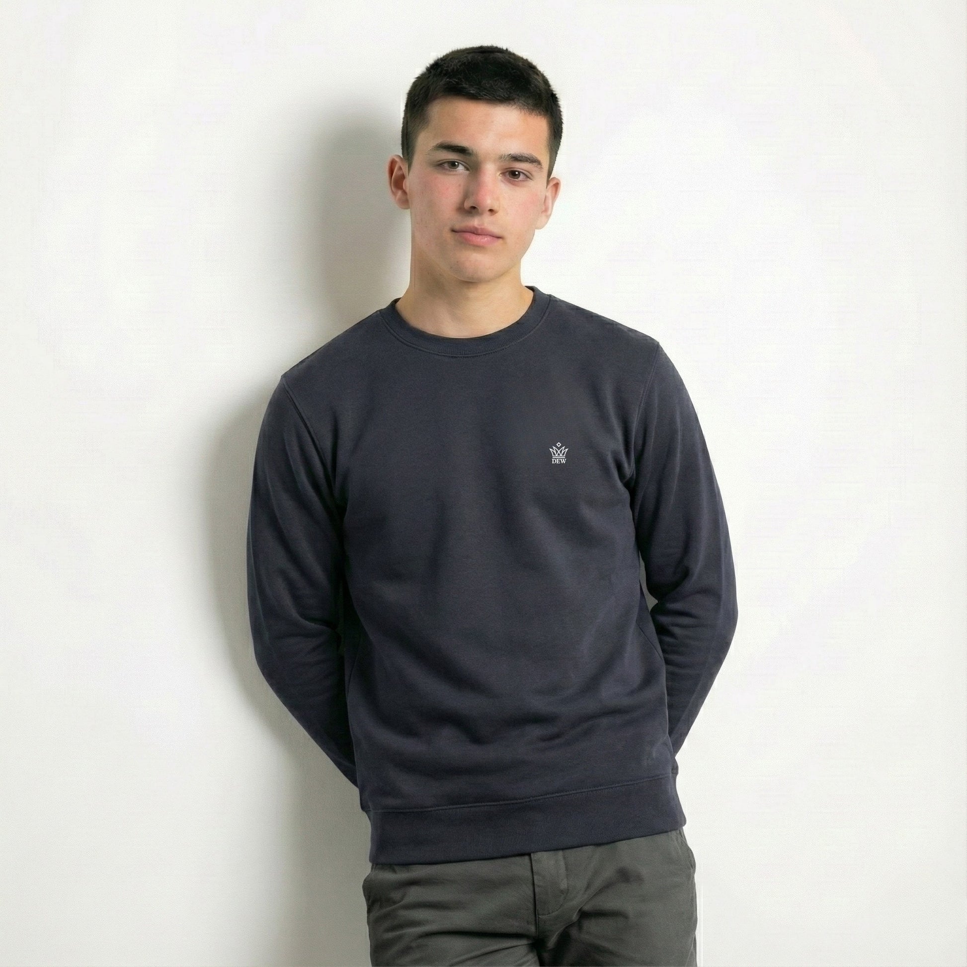 Person wearing a dark gray sweatshirt with a small logo on a white background