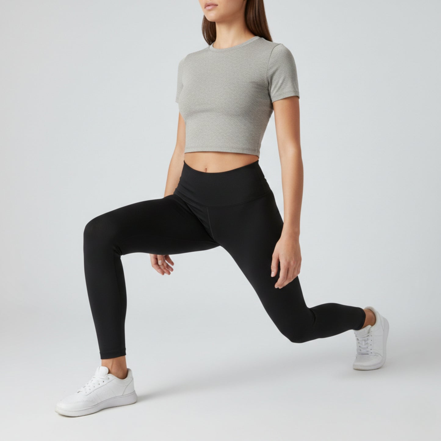 Person wearing a gray crop top and dew black leggings on a white background