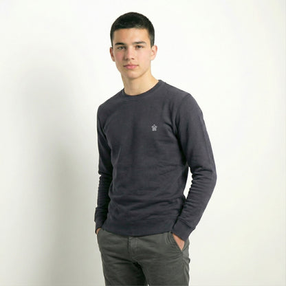 Man wearing a dark gray sweater with a small logo on a white background