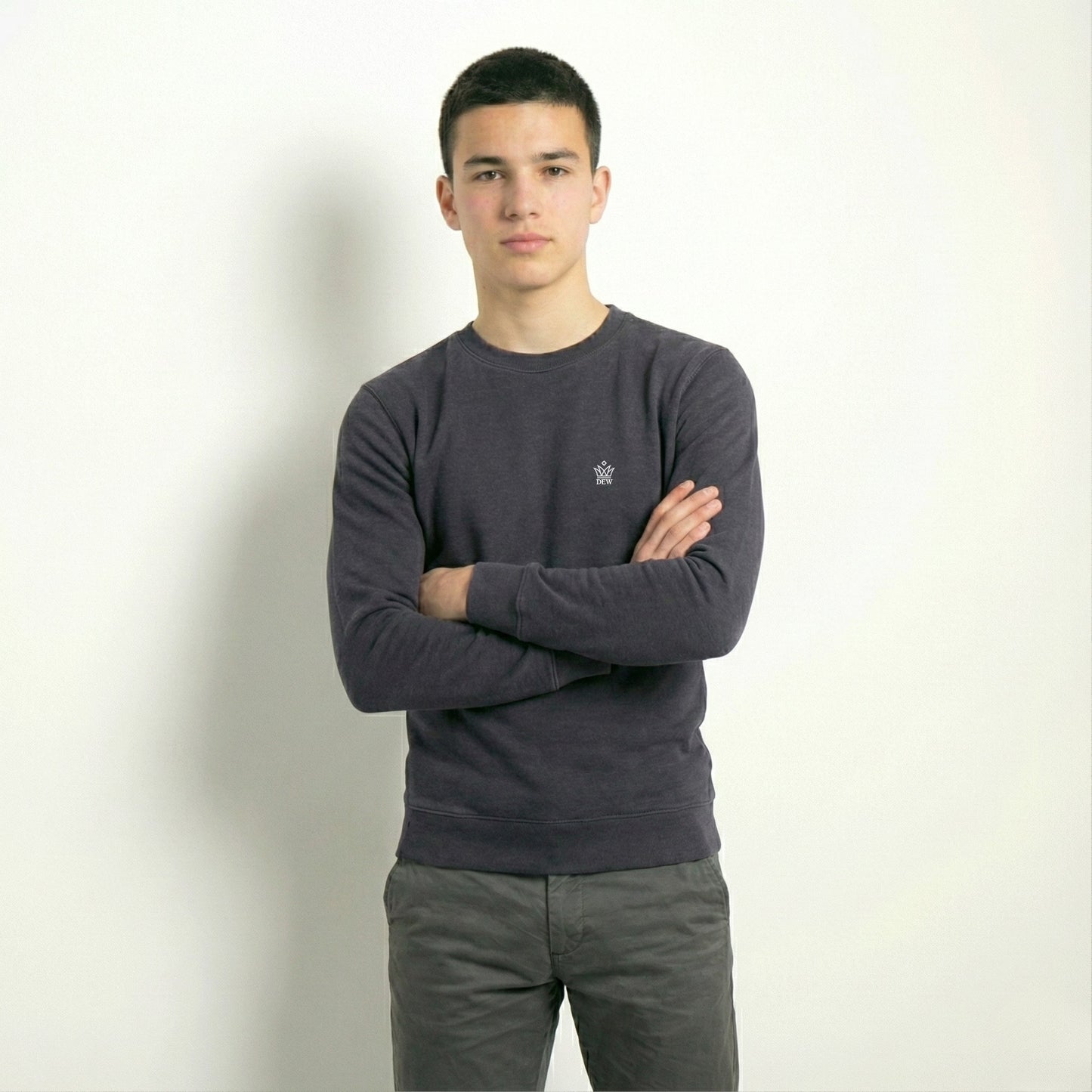 Person wearing a dark gray sweater with a small logo on a plain background