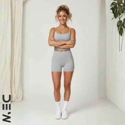 Woman wearing DEW gray luxe cami  standing in a minimalistic room with a plant.