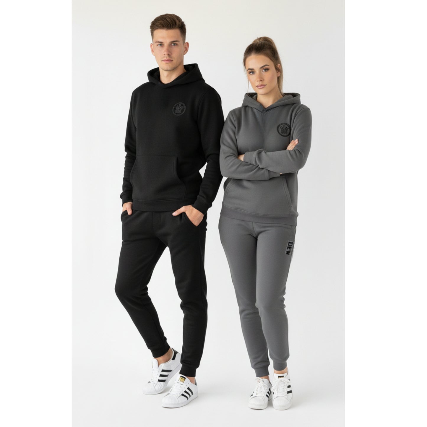 Two people wearing black and gray tracksuits with a logo on a white background