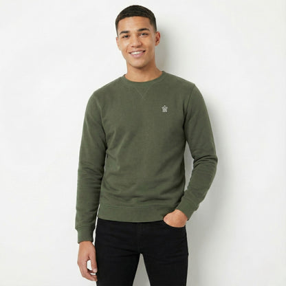 Man wearing a green sweatshirt with a small logo on a white background