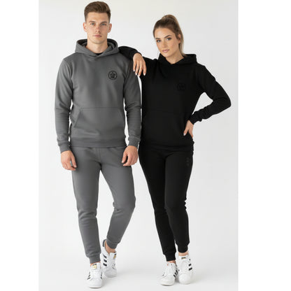 Two people wearing matching gray and black tracksuits on a white background