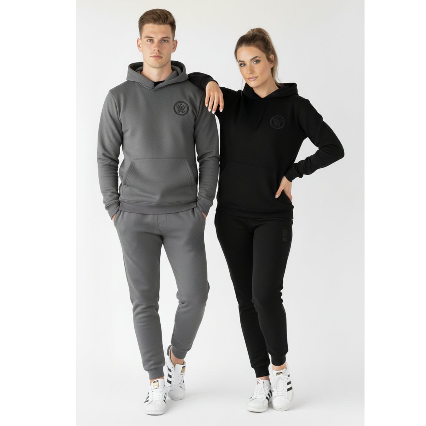 Two people wearing matching gray and black tracksuits on a white background