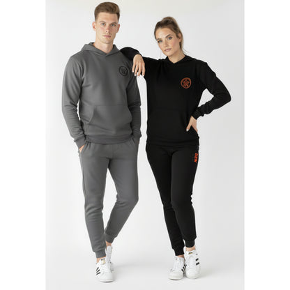 Two people wearing matching gray and black tracksuits with a logo on a white background