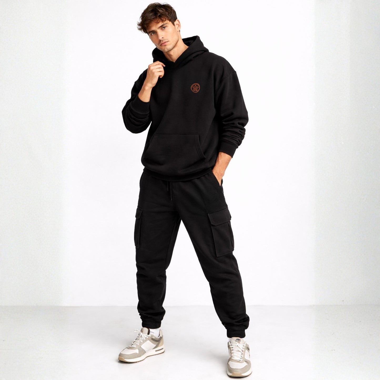 Man wearing a black hoodie and cargo pants with a white background