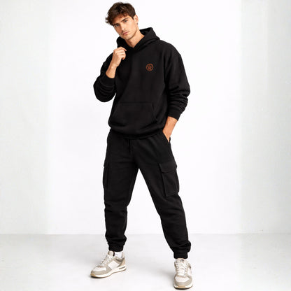 Man wearing a black hoodie and cargo pants with a white background