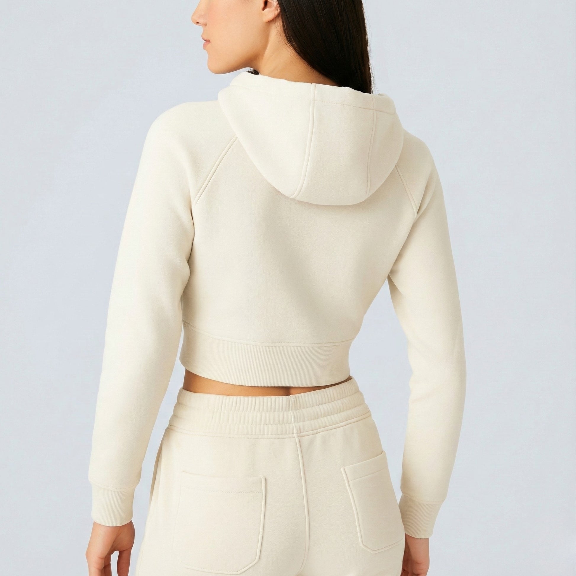 Person wearing a Cream Dew Women's Premium Crop Zip Jacket and pants on a light gray background