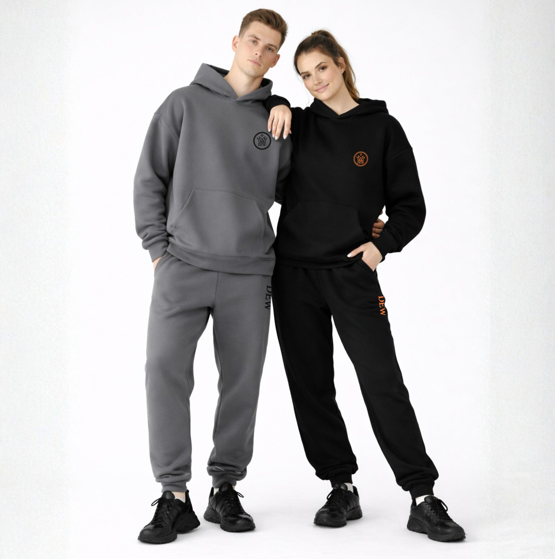 Two people wearing gray and black tracksuits with logos on a white background