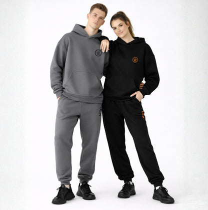 Two people wearing gray and black tracksuits with logos on a white background