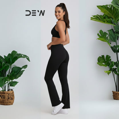 Woman wearing black seamless sports bra and high-waist seamless leggings set. Minimalist studio shot highlighting fit and DEW logo.