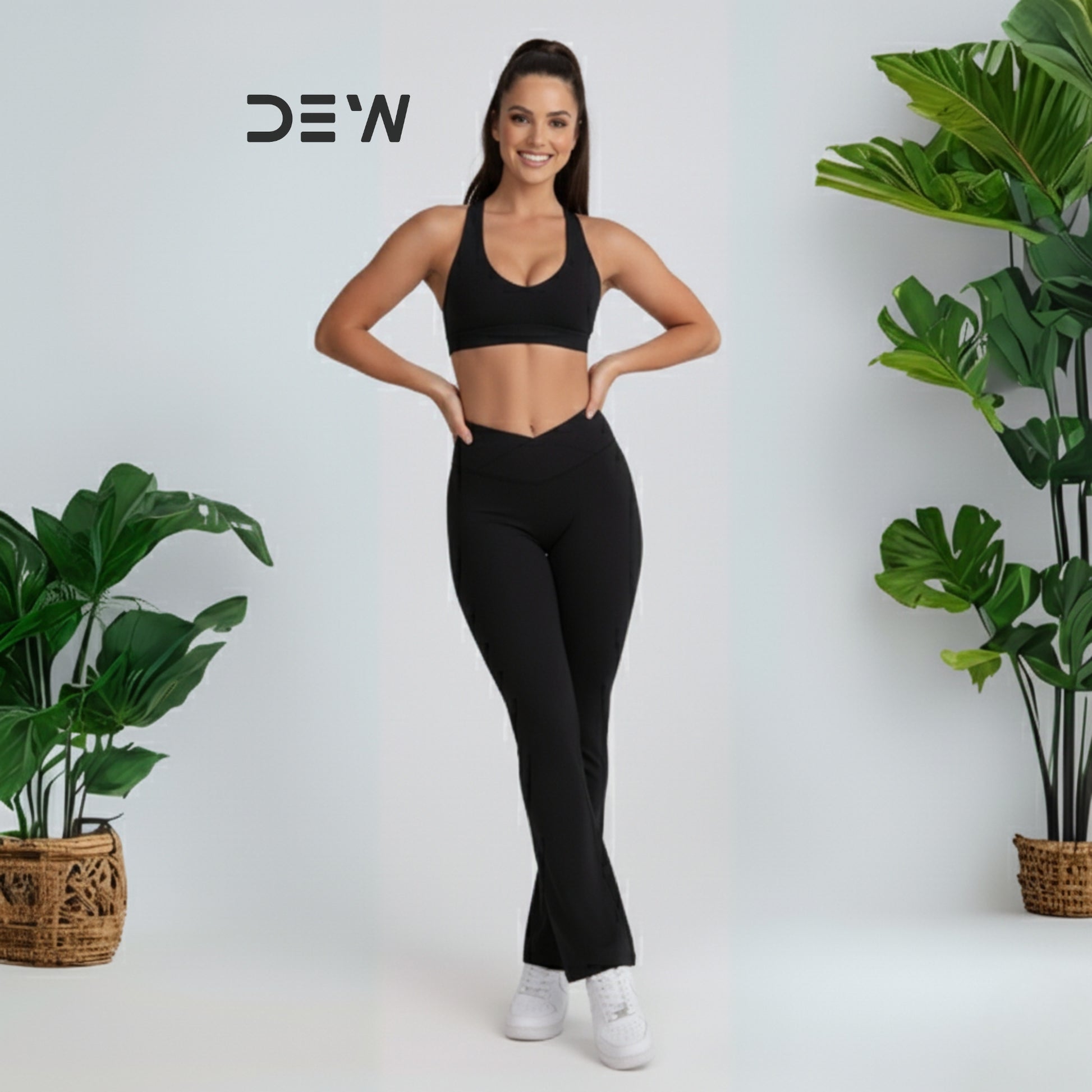 Woman wearing black seamless sports bra and Flow Fit Flare leggings. Studio pose with plants, highlighting fit and flare design.
