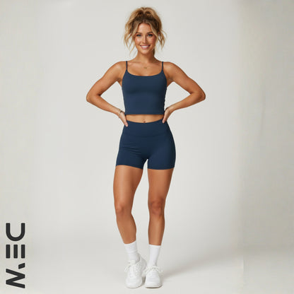 Woman wearing a navy blue dew luxe cami with 'DEW' logo on a white background