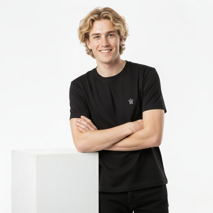 Person wearing a DEW 100% Cotton black t-shirt  with a small DEW embroidered logo, standing against a white background