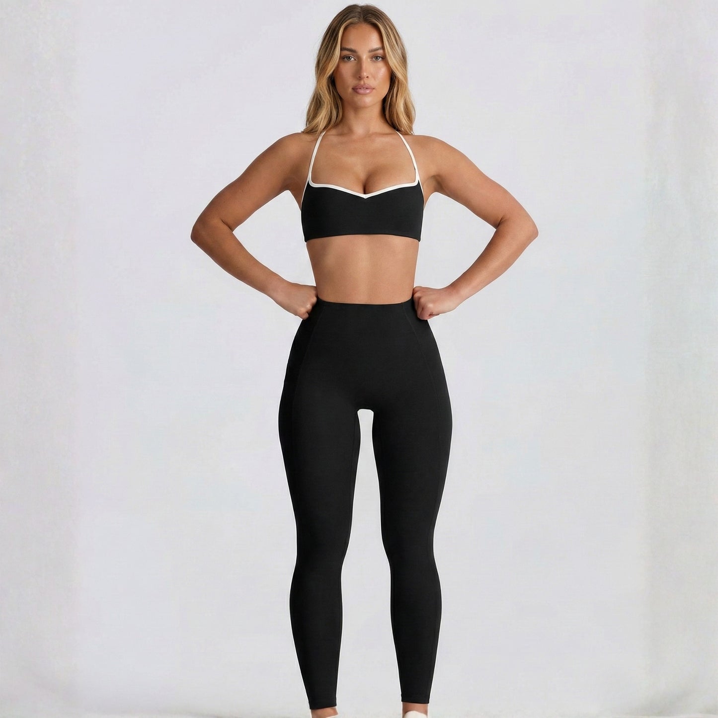 Woman wearing a black DEW Elevate sports bra and leggings on a white background