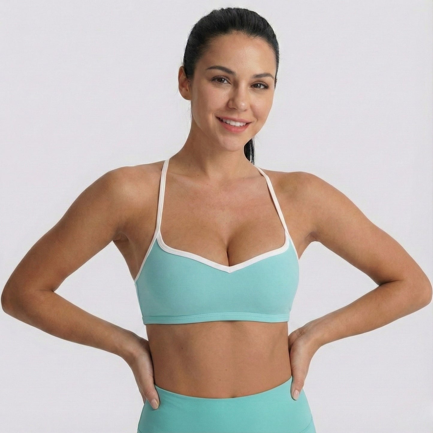 Woman wearing a DEW Elevate sports bra and leggings on a plain background