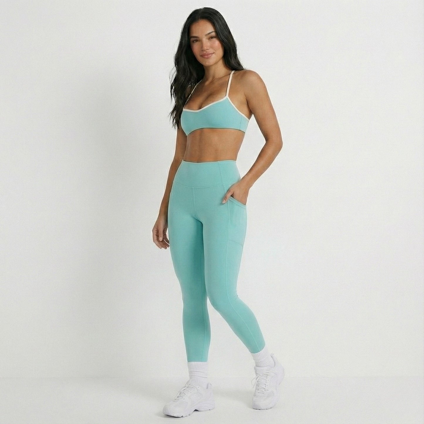 Woman wearing a DEW Elevate bra and athletic outfit on a white background