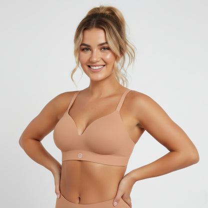 Woman wearing a beige DEW Seamless Sculpt bra and leggings on a light gray background
