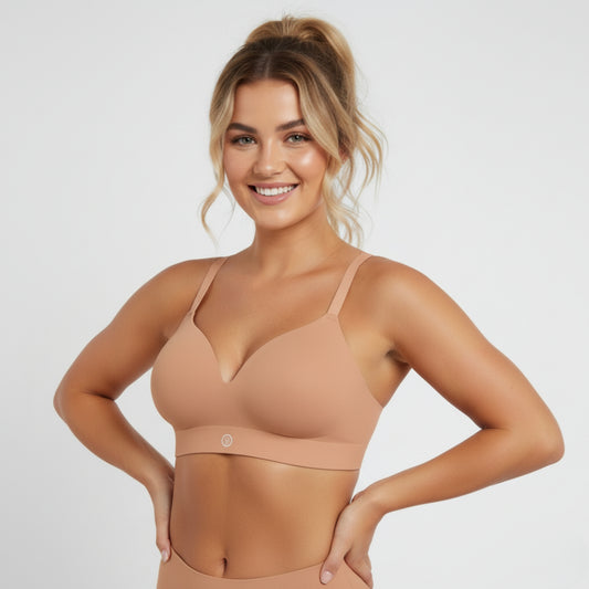 Woman wearing a beige DEW Seamless Sculpt bra and leggings on a light gray background