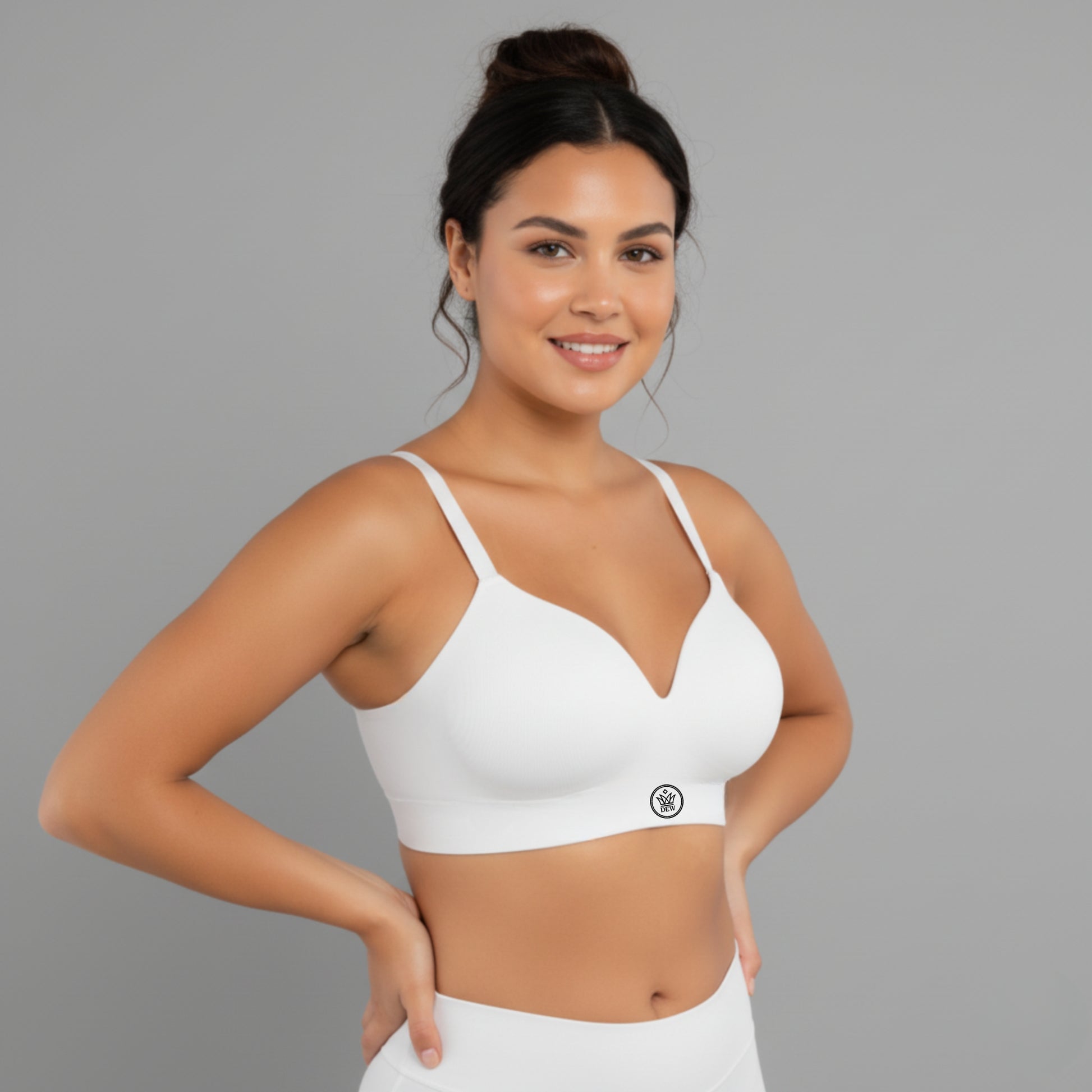 Woman wearing a white DEW Seamless Sculpt Bra with a gray background