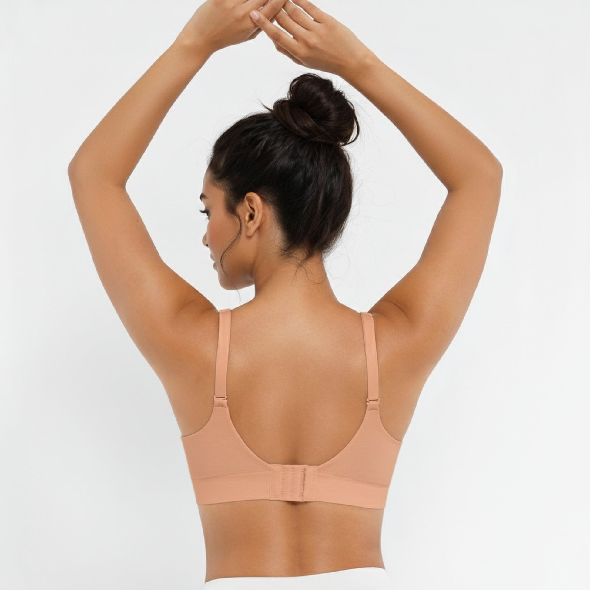 Woman wearing a beige DEW Seamless Sculpt Bra on a white background