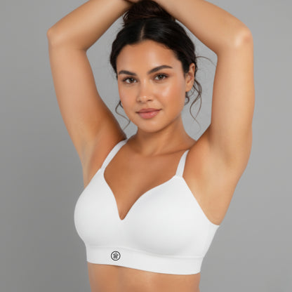 Woman wearing a white DEW Seamless Sculpt Bra against a gray background