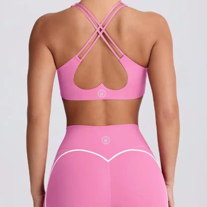 woman wearing DEW™ Women’s Sculpt Seamless Shorts - Pink Blush and DEW™ Strappy Heart Flex Sports Bra - Pink Blush, Pink sports bra and leggings set on a plain background