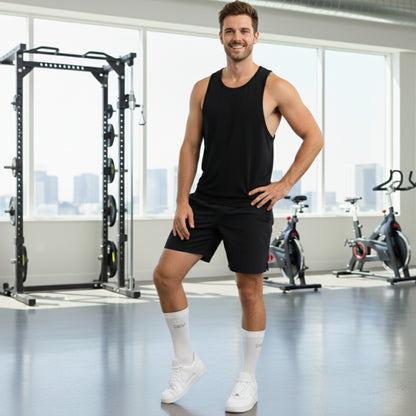 Man in black tank top and shorts wearing Dew 100% Bamboo socks standing in a gym.
