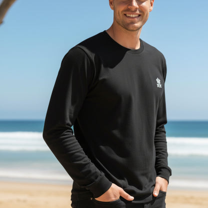 Man wearing a  Dew 100% Cotton black sweatshirt with a logo on a beach