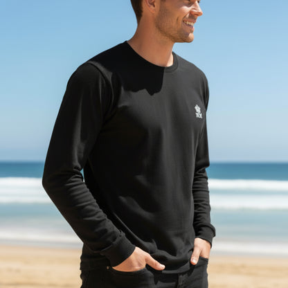 Man wearing a  Dew 100% Cotton black long-sleeve shirt with a logo on a beach
