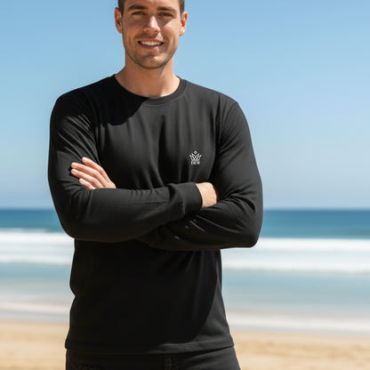 Man wearing a  Dew 100% Cotton black long-sleeve shirt with a logo on a beach