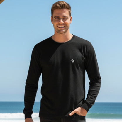 Man wearing a Dew 100% Cotton black long-sleeve shirt with a logo on a beach