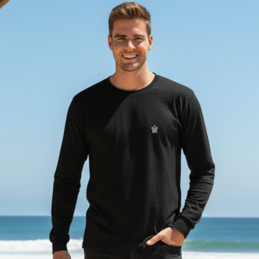 Man wearing a Dew 100% Cotton black long-sleeve shirt with a logo on a beach